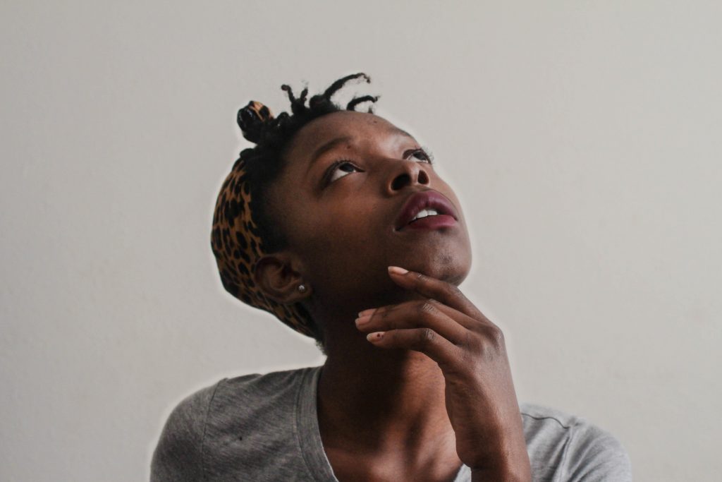 Woman with hand under chin looking up at ceiling at something. Noticing what's there and what's going on stimulates your brain.