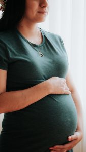 Young very pregnant woman smiling contentedly, holding her belly. Is this a long term investment, like learning about the way you move?