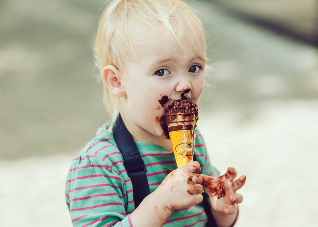 Toddler eating chocolate ice cream with it all over his face. Instant gratification is great but long term movement work will help this child avoid neck and shoulder pain in adulthood, making it easier to get the ice cream into his mouth when he's in his 70s.
