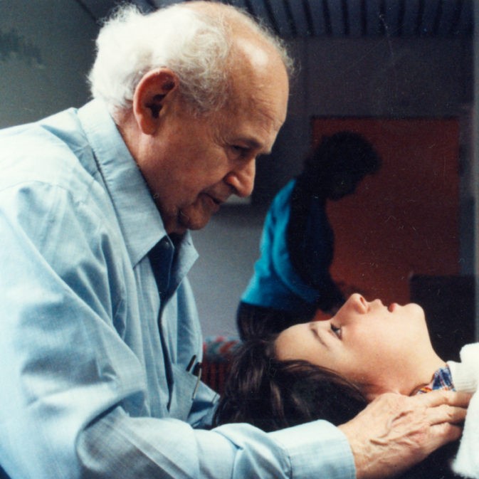 Dr Moshe Feldenkrais giving a private hands-on session to a young girl's neck and head.