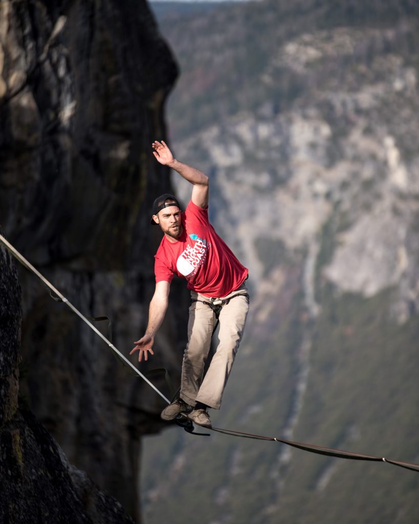 Tightrope walker working to keep balanced high above a mountain valley.