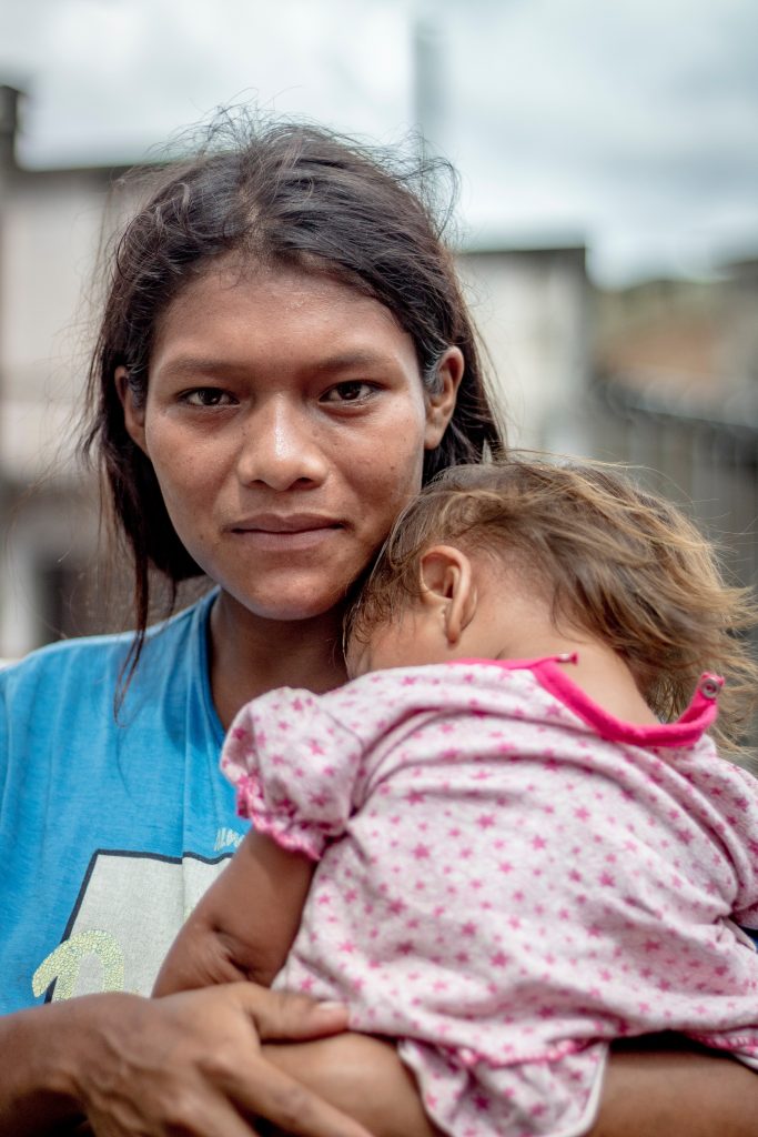 Young indigenous Peruvian woman cradling her sleeping child.